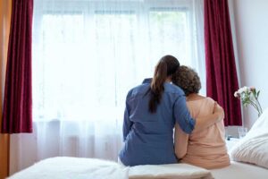 Older adult arranging familiar belongings in a bright assisted living apartment with family nearby.