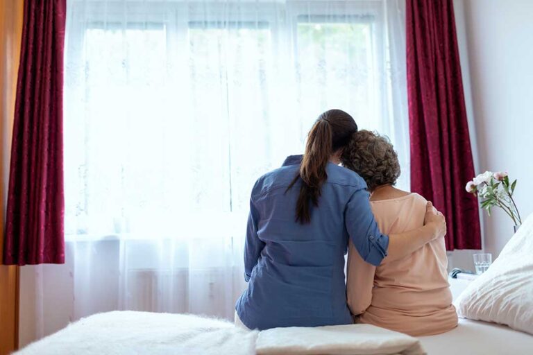 Older adult arranging familiar belongings in a bright assisted living apartment with family nearby.