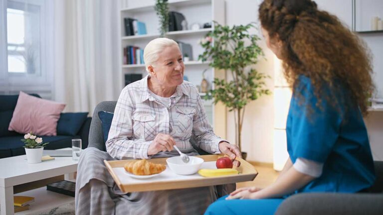 Adult child reviews a care plan with an older parent at a bright assisted living table.